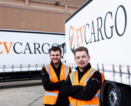 Two EV Cargo employees standing next to EV Cargo lorries