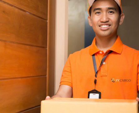 EV Cargo courier in orange branded polo shirt delivering parcel